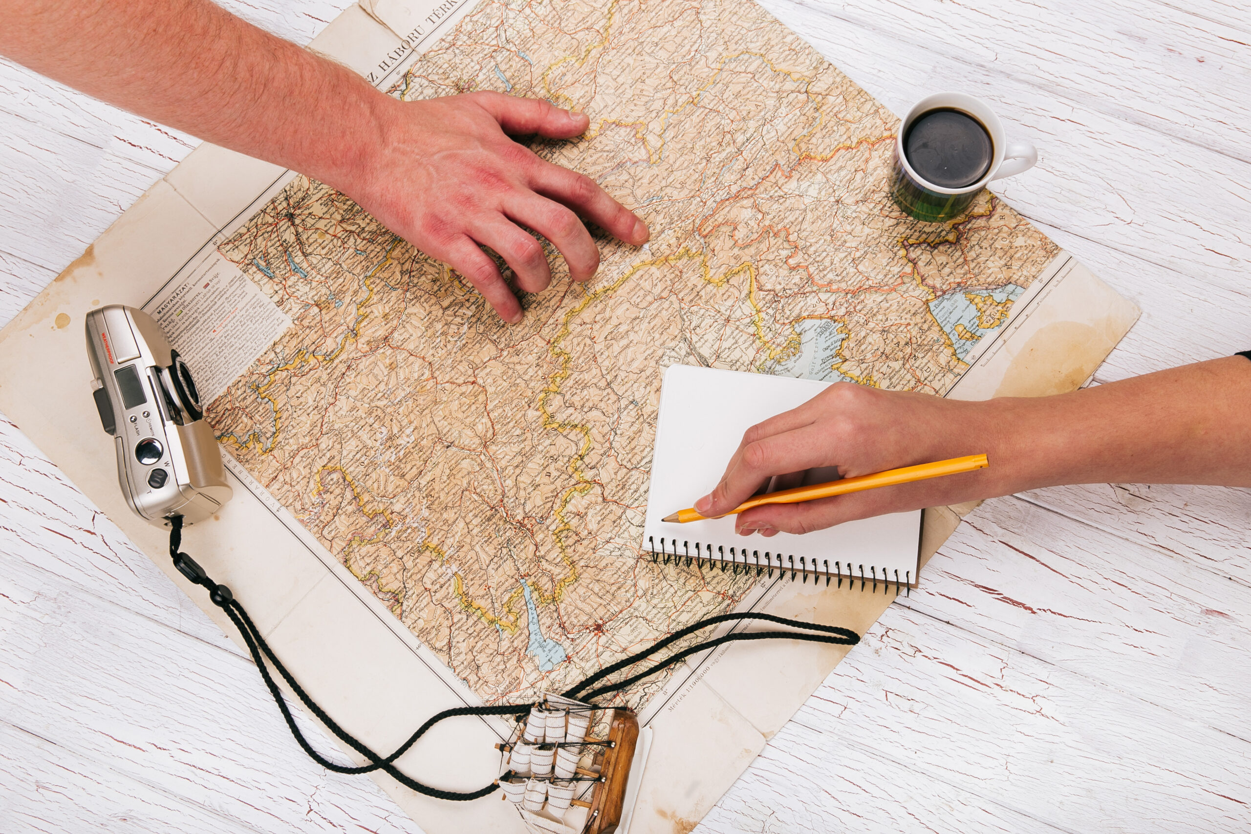 Men hold their hands on map with coffee, cmaera and notebook